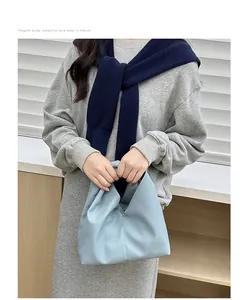 Close-up of light blue pleated croissant bag made of textured faux leather with knotted handle