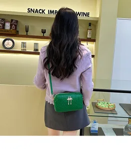 Green quilted crossbody bag with flamingo metal buckle shown on a model for size and fit