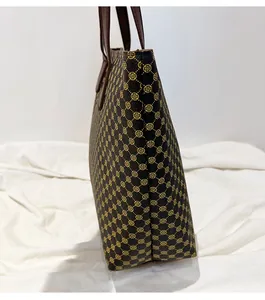 Side view of large brown tote bag showing textured classic pattern and handle stitching