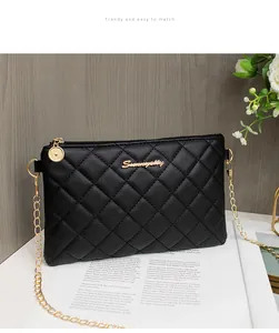 Détail d'un sac à bandoulière noir matelassé avec logo doré et fine bandoulière chaîne