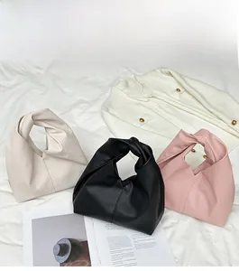 Detailed view of cloud bags with twisted handles in cream, black, and pink colors