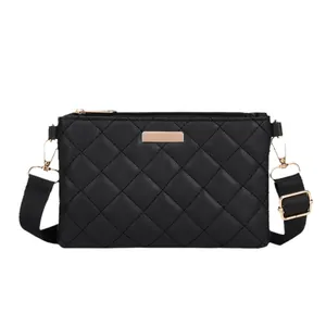 Quilted black crossbody square bag with gold hardware and adjustable strap on white background