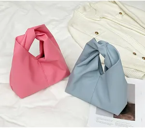 Detail of pink and blue knotted handle handbags with lychee grain leather texture