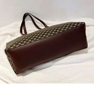Detail view showing the wide bottom structure and monogram print of this brown tote bag