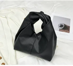 Detail of the black pebbled leather texture and elegant knot handle on a cloud bag