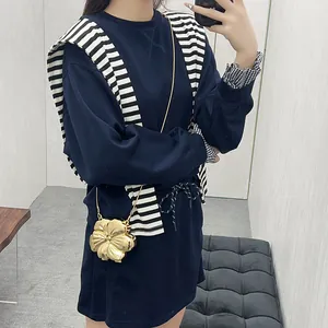 Set minimalista felpa e gonna blu navy con una borsa a tracolla a forma di fiore dorato