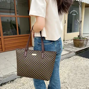 Outdoor shot of a vintage geometric pattern tote bag with gold logo and leather handles