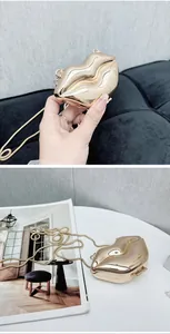 Detail of a shiny gold lip-shaped clutch bag with sleek metal snake chain strap