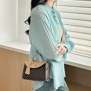 Brown geometric print crossbody small square bag with chain strap shown on model