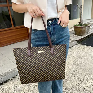 Detail of vintage geometric pattern tote bag with brown leather handles and gold nameplate