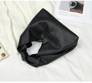 Close-up of black lychee texture knot bag on white fabric with minimalist styling