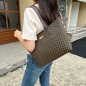 Close-up of brown leather strap and gold geometric pattern on vintage tote bag