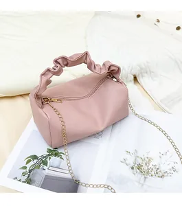 Detail of pink lychee pattern bag featuring a gathered handle and gold chain strap