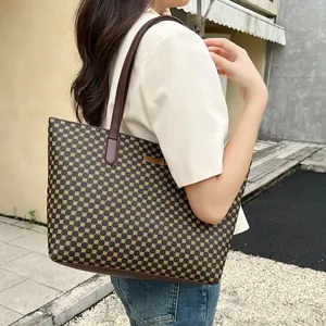 Detail view of large brown tote bag with vintage geometric floral pattern and metal logo