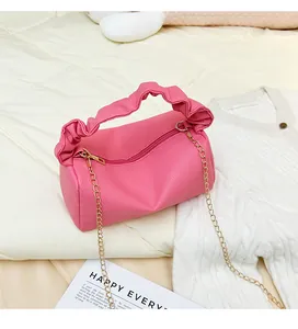 Detailed close-up of pink lychee textured leather pillow bag with gold chain and handle