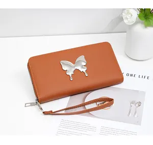 Close-up of a long brown faux leather wallet with a silver butterfly ornament and wrist strap