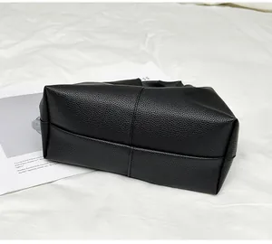 Close-up of cross-seam stitching on black lychee texture leather handbag base
