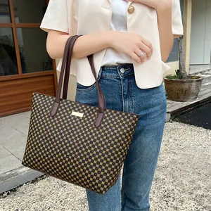 Close-up of stylish brown geometric pattern tote bag with leather handles on shoulder