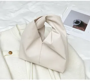 Detailed macro shot of cream-colored litchi grain leather and knotted handle design