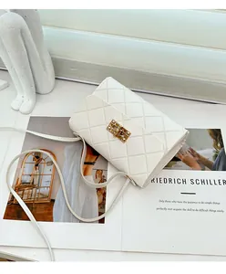 Detail van witte gewatteerde tas van kunstleer met gouden rechthoekige draaisluiting