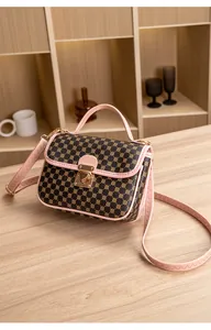 Detail of dark brown handbag with pink trim, heart buckle and adjustable strap