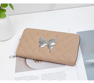 Macro detail of quilted long wallet with metallic butterfly logo on beige leather