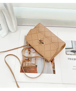 Detail van beige gewatteerde crossbodytas met gouden sluiting en leren riem op een tijdschrift
