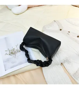Detail of black litchi grain leather crescent bag featuring a stylish scrunchie strap