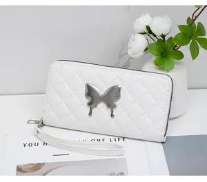 Detail of white quilted wallet with silver butterfly ornament and leather wristlet
