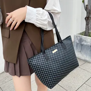Detail of minimalist black tote bag with blue dotted pattern and metal logo plate