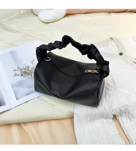 Detail of black lychee grain leather pillow bag with scrunchie handle and gold zipper