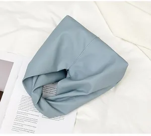 Detail of light blue cloud bag with soft pebble texture and twisted handle design