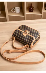 Detailed close-up of quilted Kelly bag with vintage patterns and gold metal lock on a table