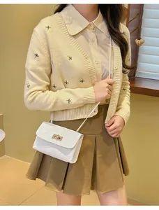 Detailed close-up of quilted white crossbody bag with golden metal twist lock and strap