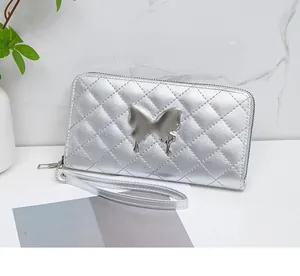 Detail of silver quilted leather long wallet with large metal butterfly and wrist strap