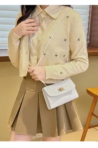 White quilted crossbody bag with gold twist lock shown on a model in a home setting