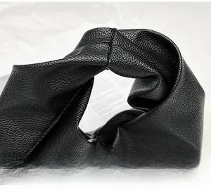 Detailed close-up of soft black lychee grain leather handle on minimalist cloud bag