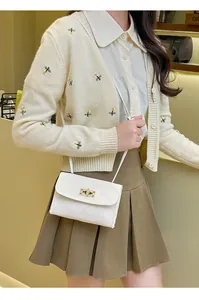 Detail of white quilted crossbody bag featuring a golden twist lock and slim shoulder strap