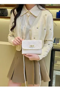 Detail of white quilted crossbody bag featuring a gold twist lock and slim PU shoulder strap