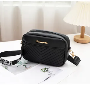 Close-up of black V-quilted leather crossbody bag with gold logo and wide logo strap