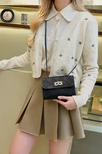 Detail einer schwarzen Stepptasche mit goldenem rechteckigem Metalldrehverschluss