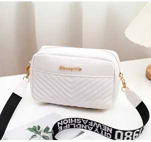 Detailed shot of white quilted PU leather crossbody bag with chic golden logo and wide strap