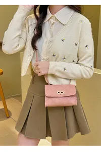 Detail view of pink quilted crossbody bag with gold twist lock on female model