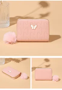 Detail of pink faux leather wallet with butterfly decor, quilting, and pompom charm