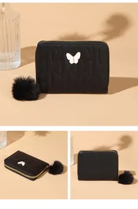 Detail of black quilted PU leather wallet with butterfly ornament and faux fur pompom