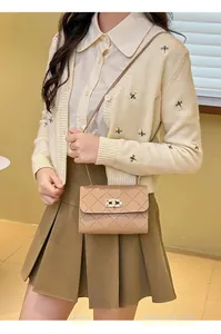 Quilted crossbody bag with gold lock buckle shown on model in warm interior lighting