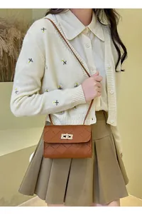 Detail of a brown quilted crossbody bag featuring a golden rectangular twist lock closure