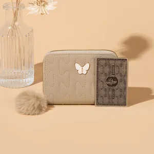 Elegant beige puzzle-stitched coin purse with metal butterfly and plush pompom charm