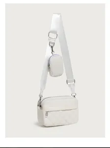 Detail of white quilted crossbody bag with wide strap and matching mini coin purse pouch