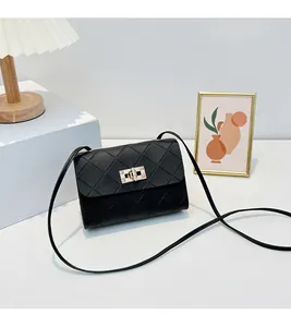 Detail of black quilted crossbody bag with golden twist lock and slim shoulder strap
